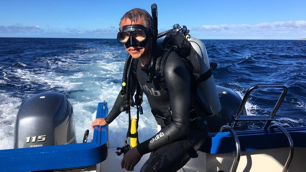 A person wearing scuba gear on a boatDescription automatically generated